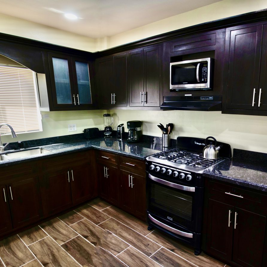 2BR Villa K+D+T kitchen with dark cherry cabinets, granite counters and gas range