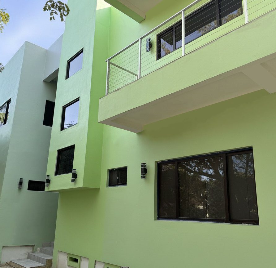 MeMe's Place Estate front exterior of green building with rooftop terrace