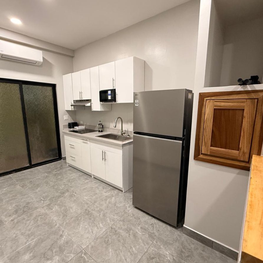 Honeycreeper Suite kitchenette with white cabinets and refrigerator