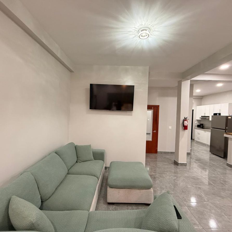 Honeycreeper Suite living area with sage sectional sofa, TV and open kitchen